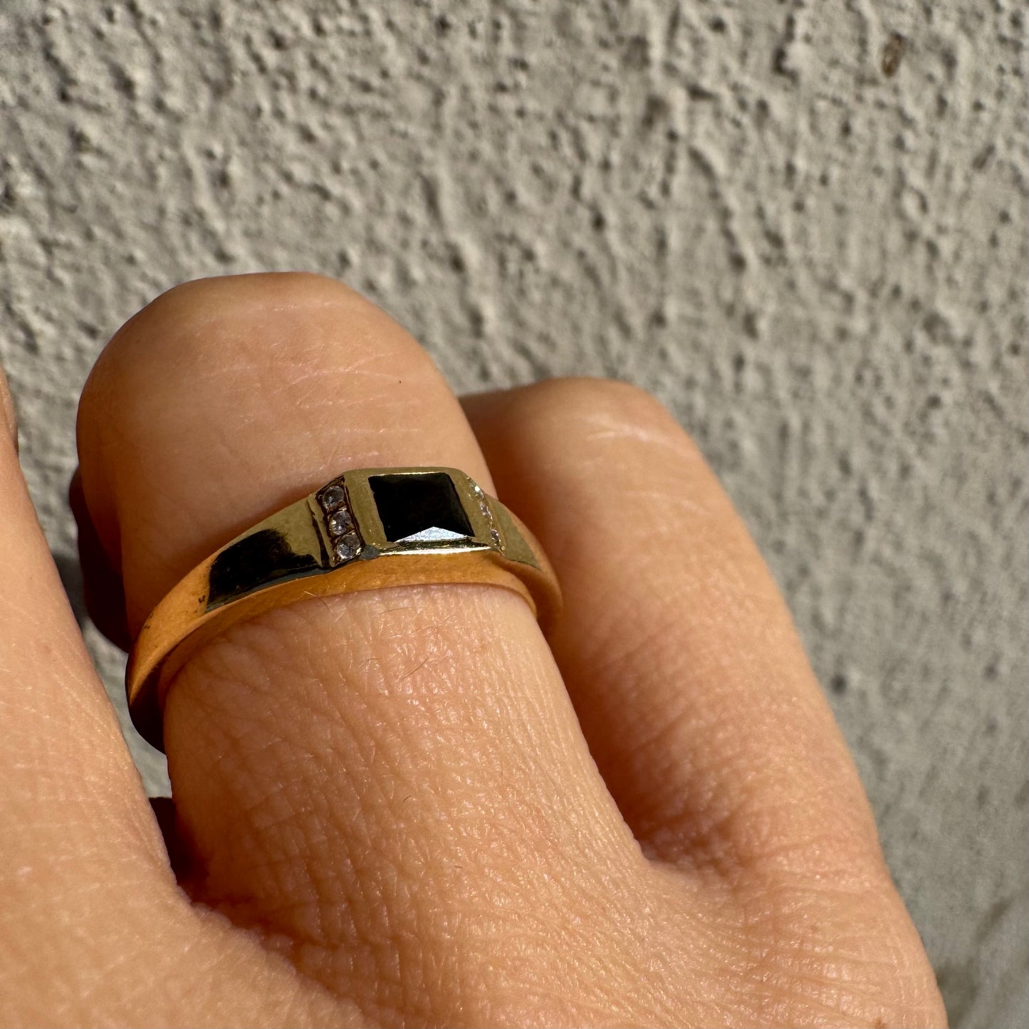 טבעת זהב 14 קראט משובצת אבן ספינל שחור בחיתוך ריבועי במרכז ויהלומים קטנים משני הצדדים.