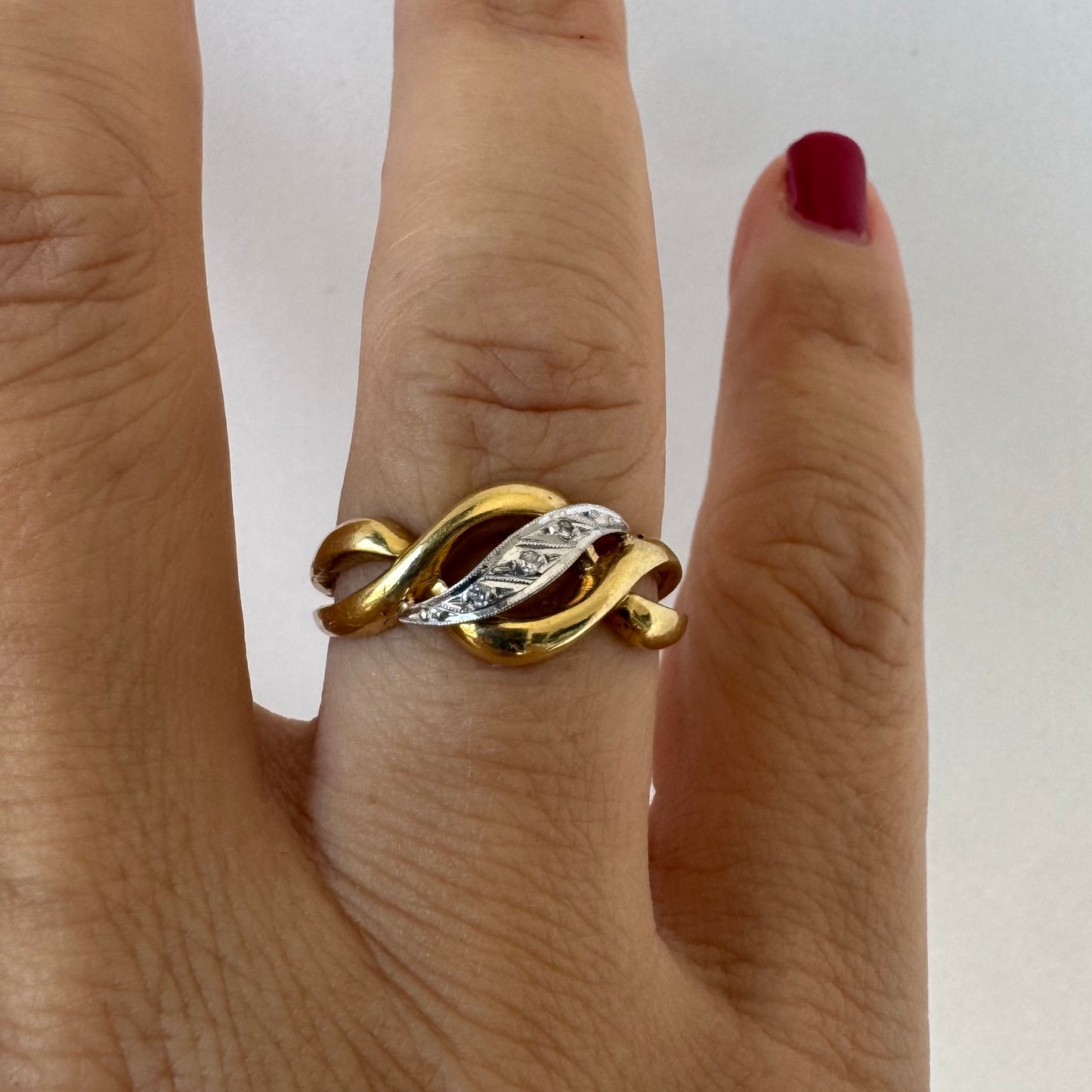 18K gold knot-style ring featuring a white gold center accented with delicate Diamonds.