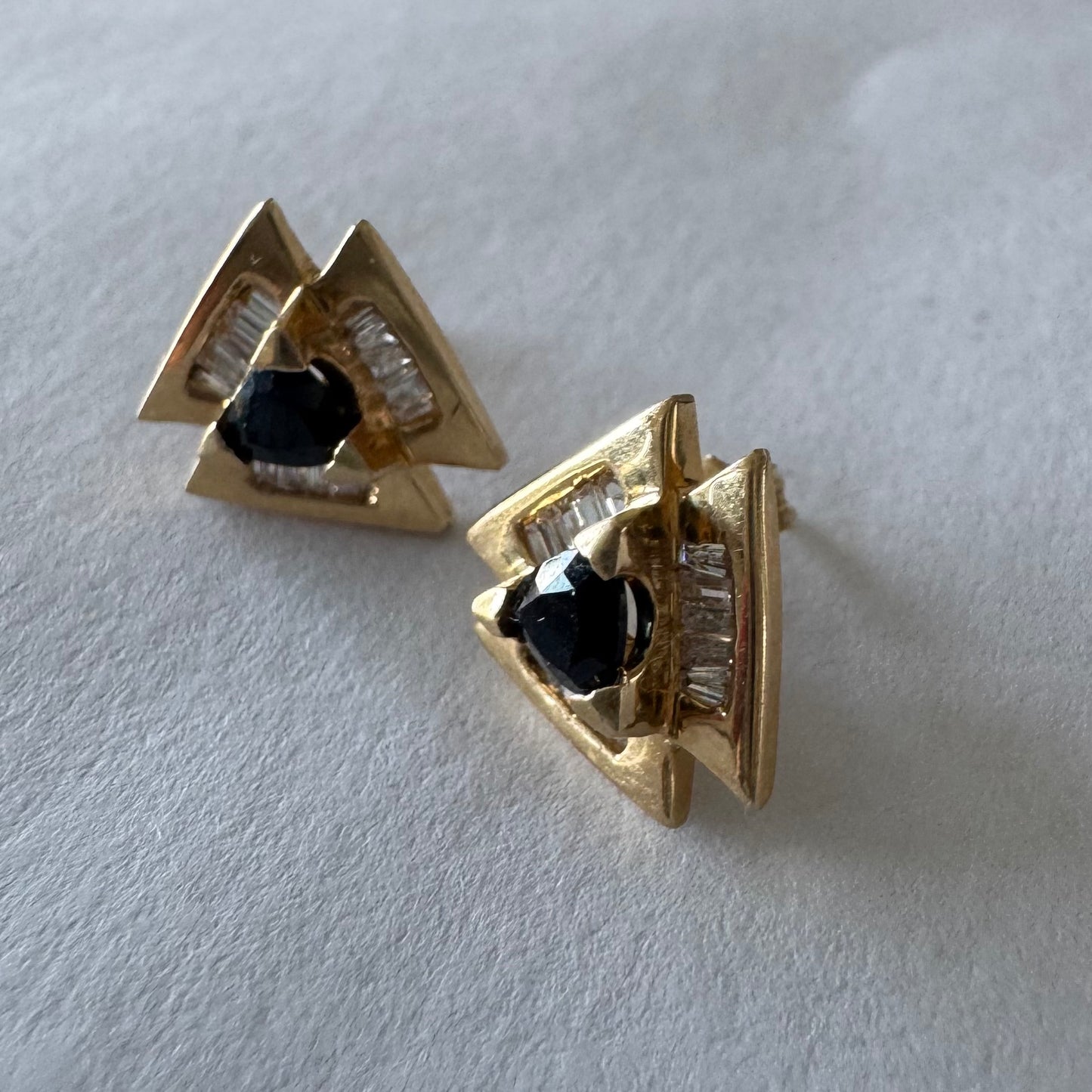 14K gold geometric stud earrings set with a Sapphire stone, surrounded by baguette Diamonds.