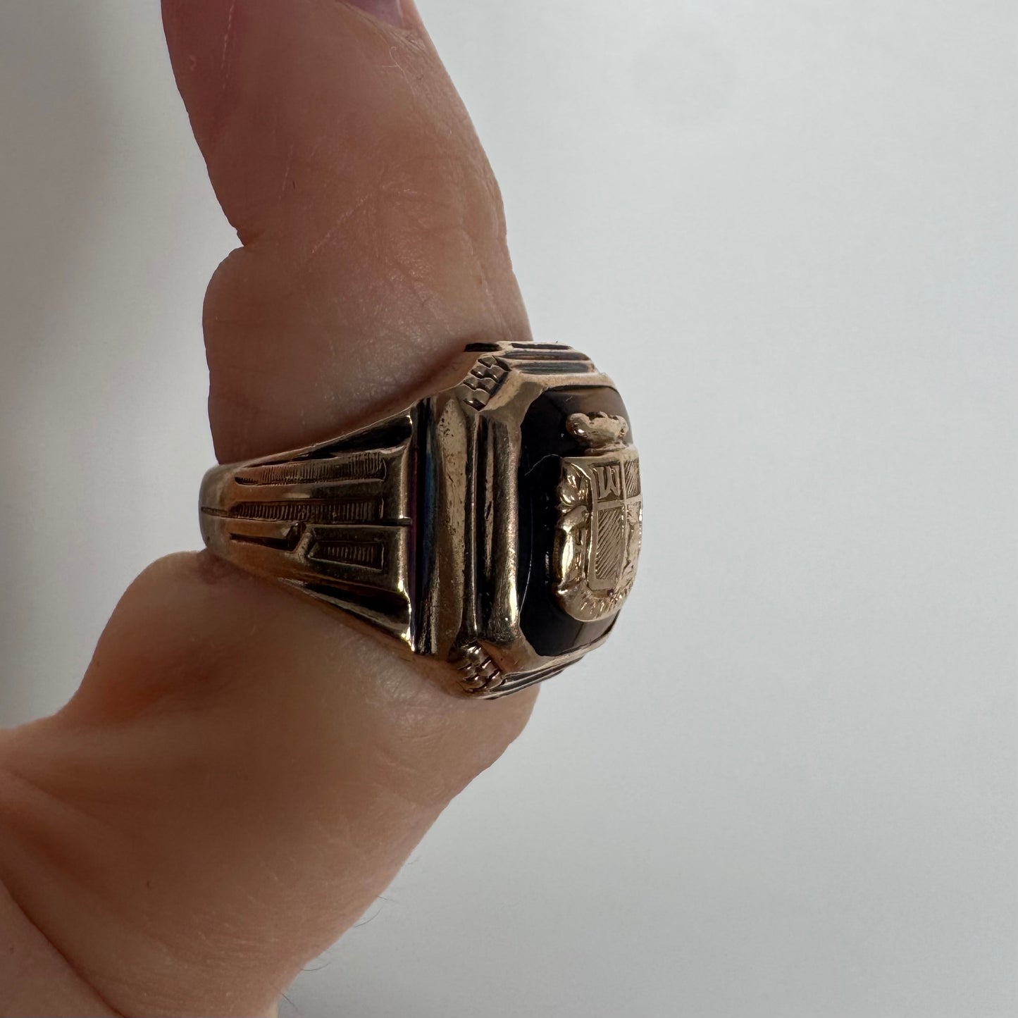 טבעת חותם זהב צהוב 10 קראט עם אבן בגוון חום-דבש ועיטור סמל מובלט במרכז.