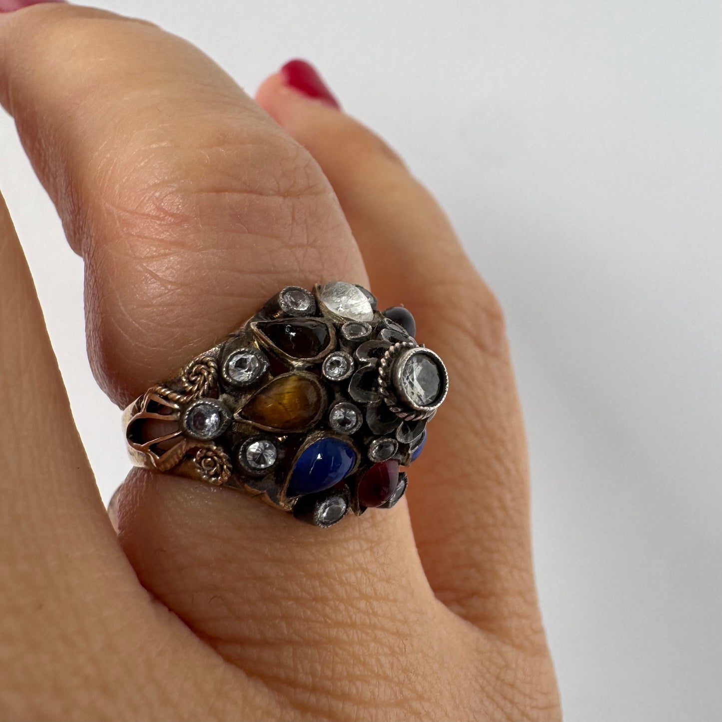 14K gold ring set with a central transparent gemstone surrounded by a vibrant mosaic of colorful gemstones -set in an ornate, handcrafted design