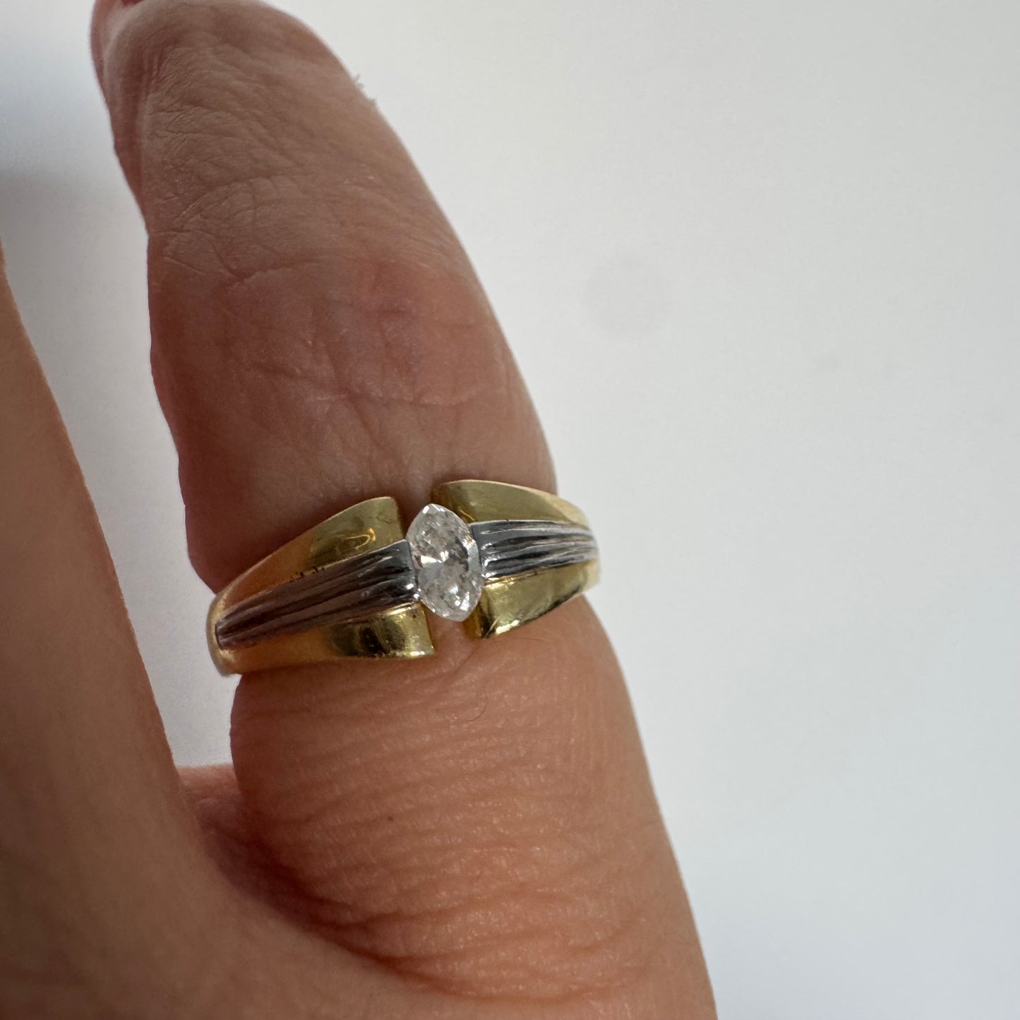 טבעת זהב 18 קראט בעיצוב דו-גוני של זהב צהוב ולבן, משובצת יהלום בחיתוך מרקיזה. 
