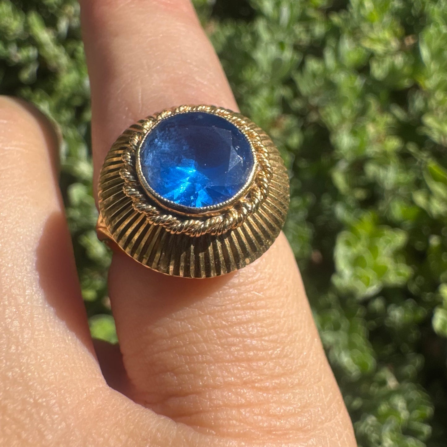 18K gold ring featuring a vibrant round Blue Topaz set in a textured gold bezel.