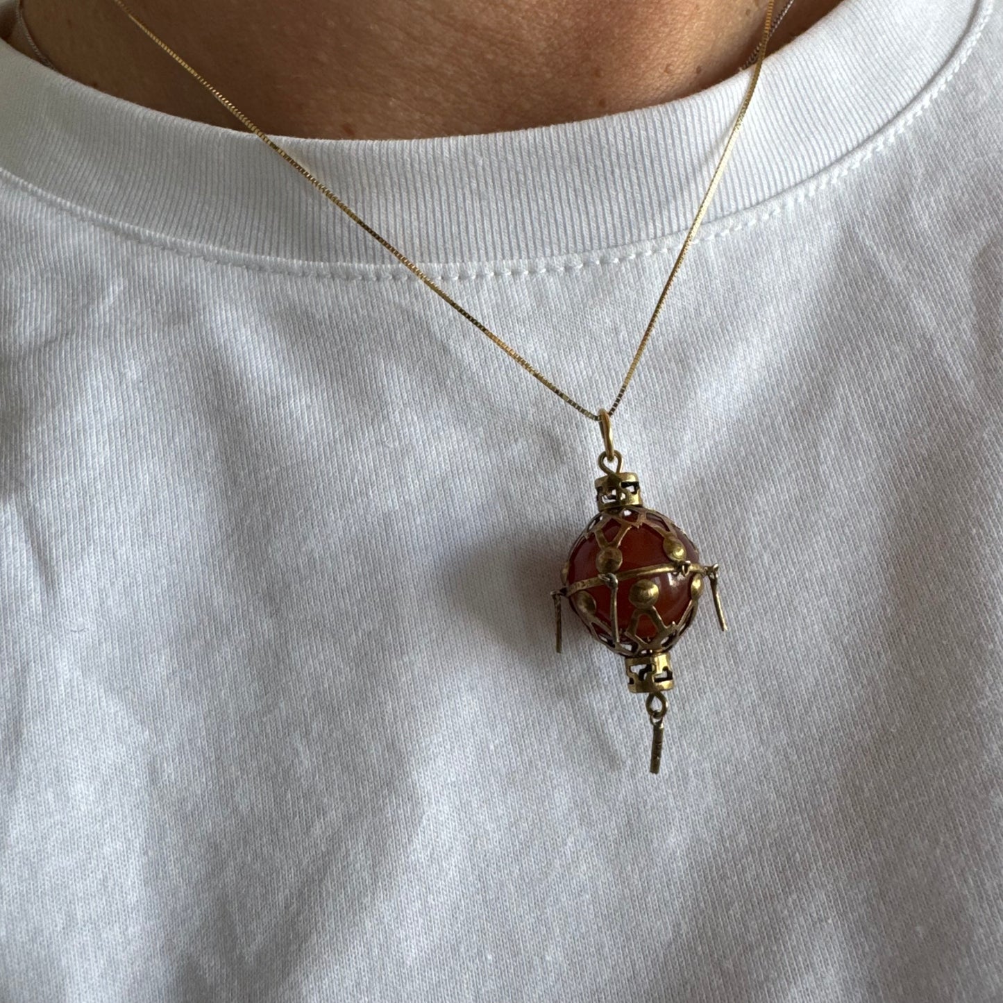9K gold pendant set with a deep red stone in an intricate openwork design.