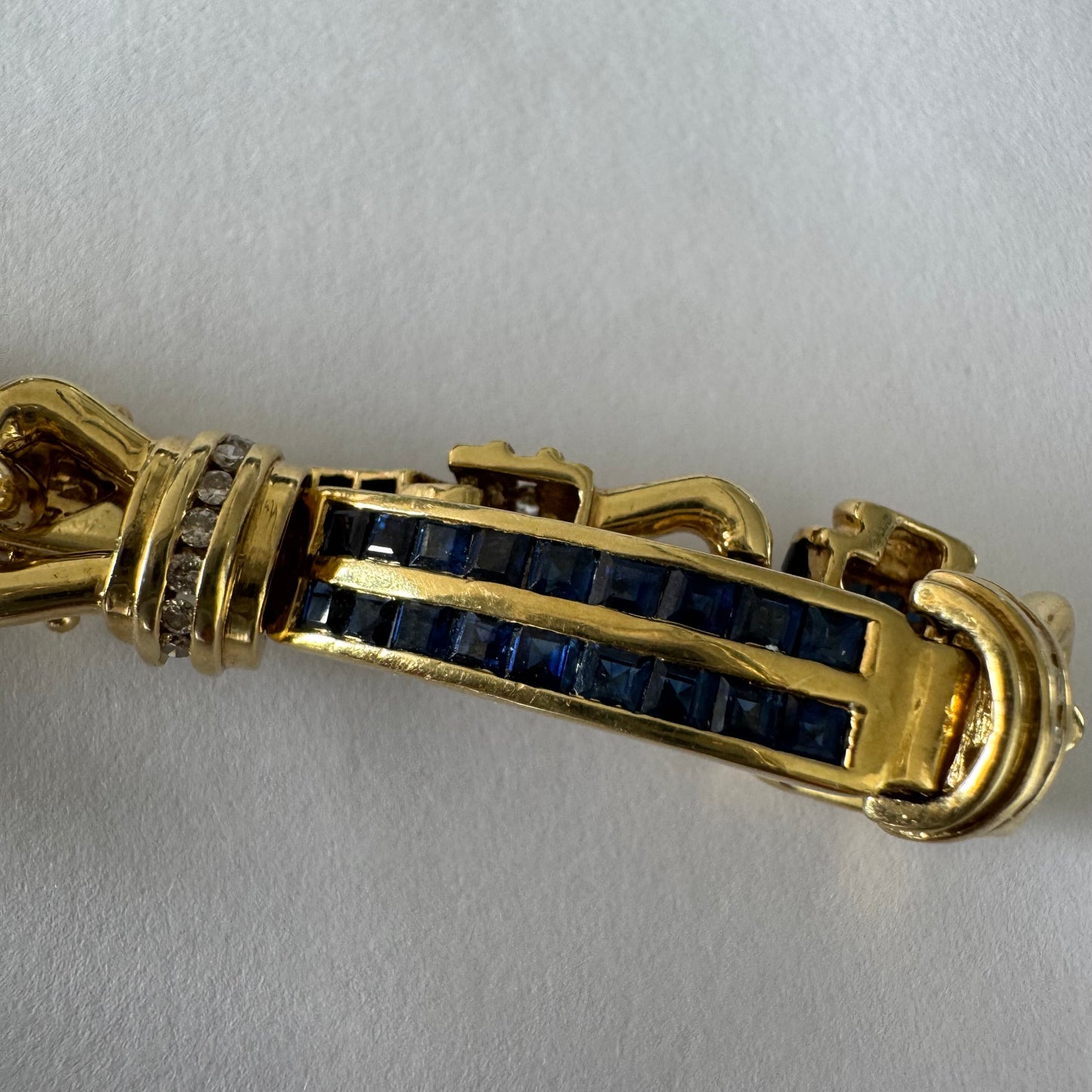 18K gold bracelet featuring a bold link design set with deep blue Sapphires and a subtle Diamond accent at the center.
