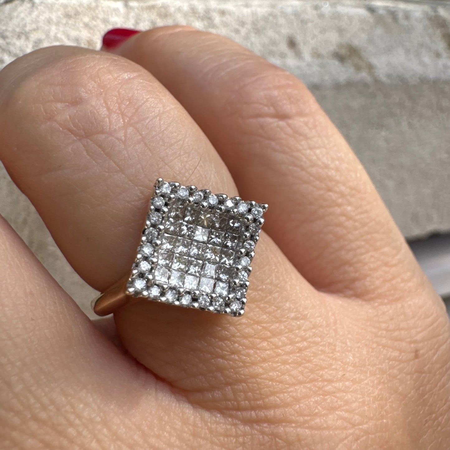 טבעת זהב 14 קראט בעיצוב ריבועי משובצת יהלומים בחיתוך פרינסס ומוקפת מסגרת יהלומים עגולים. 