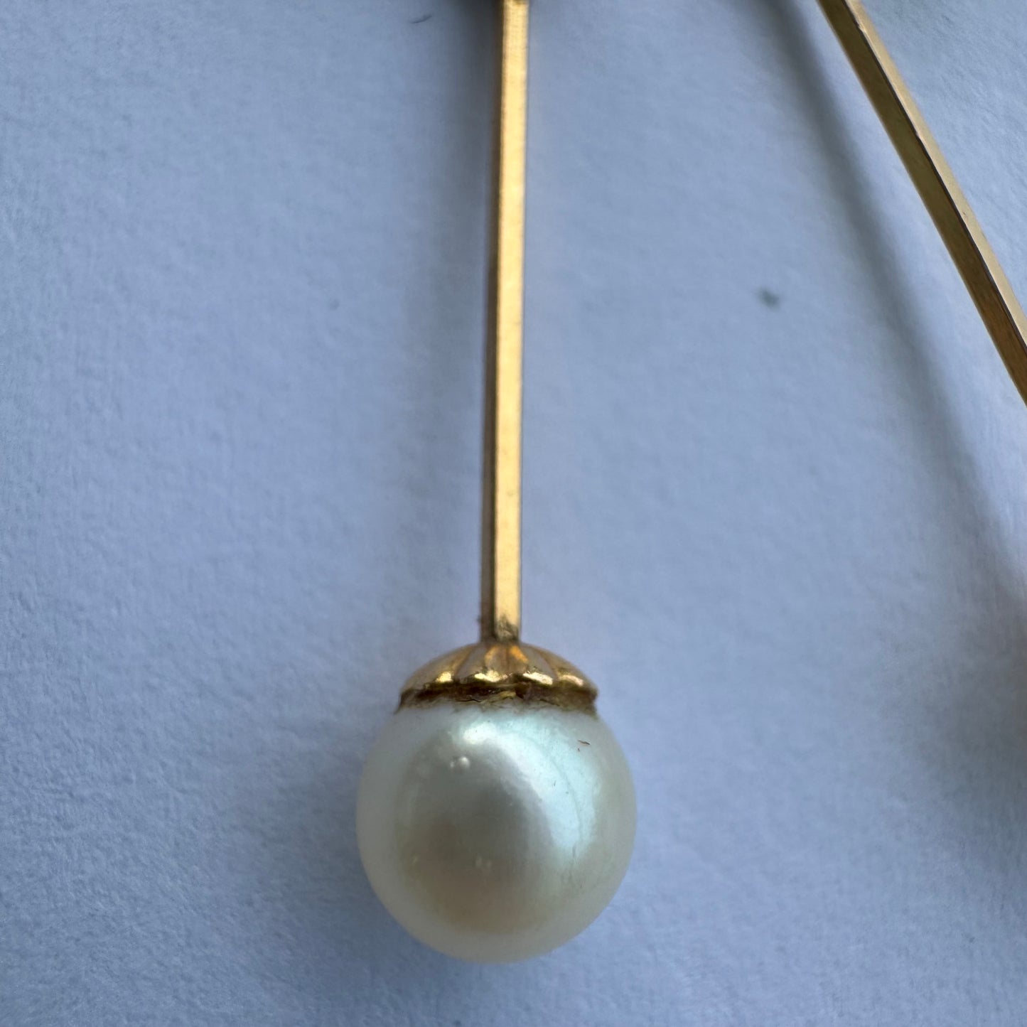 עגילי זהב 14 קראט בעיצוב תלוי ועדין, עם פנינה עגולה בקצה.