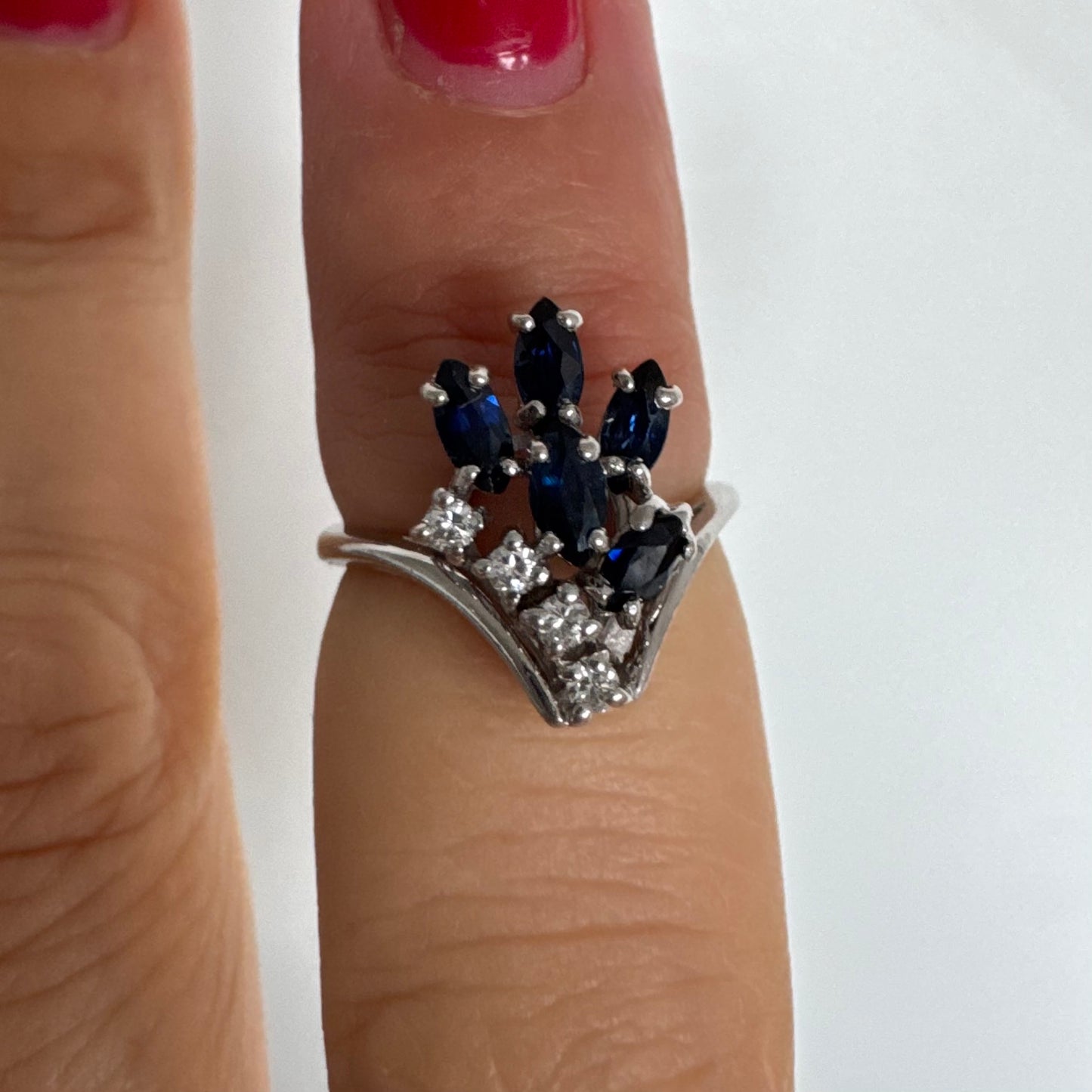 טבעת זהב לבן 14 קראט משובצת אבני ספיר כחולות בחיתוך מרקיזה ויהלומים, היוצרים מראה אלגנטי ודינמי.