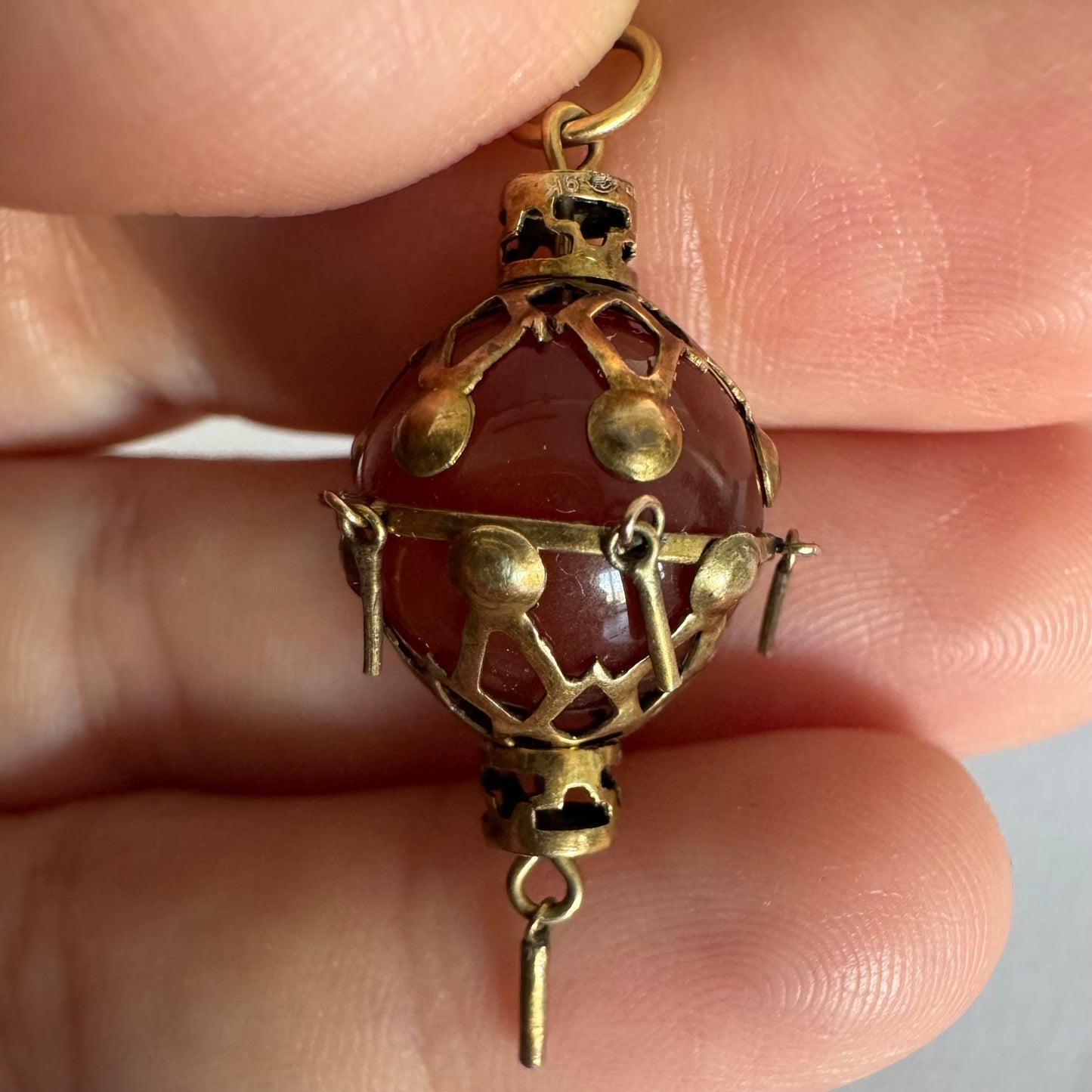 9K gold pendant set with a deep red stone in an intricate openwork design.