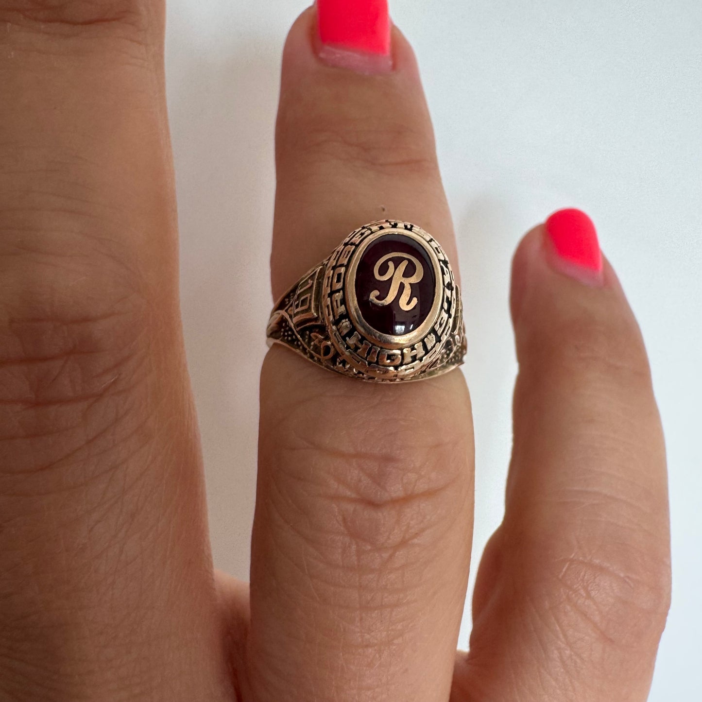 10K gold class ring featuring a rich red center stone engraved with the letter “R”.