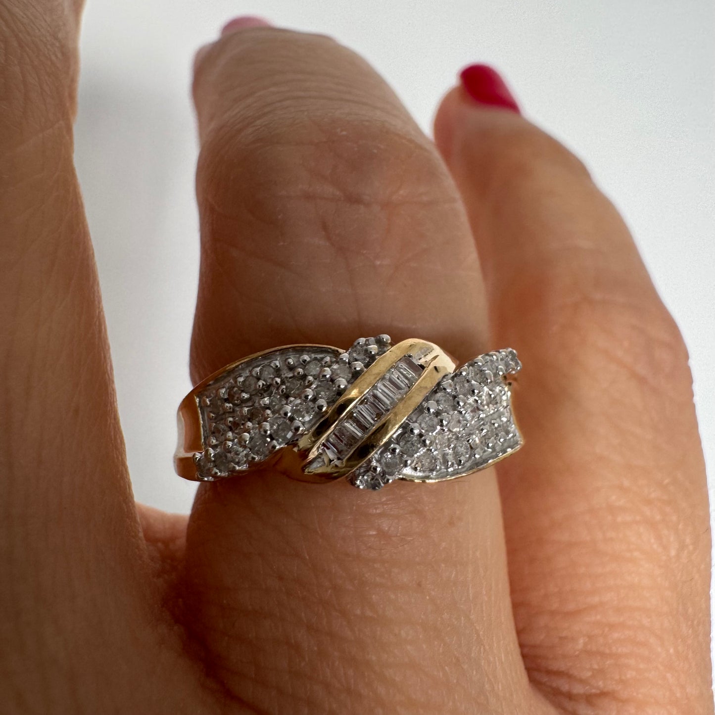 טבעת זהב 10 קראט משובצת יהלומים בחיתוך עגול לצד שורת יהלומי בגט במרכז.