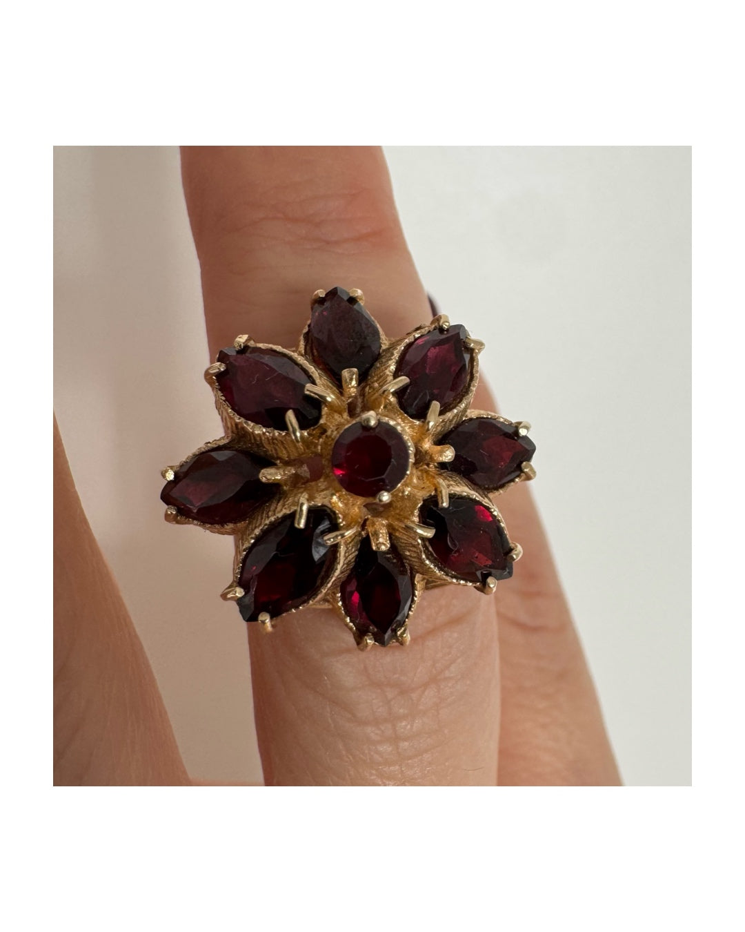 14K gold ring set with marquise-cut Garnets surrounding a round central stone.