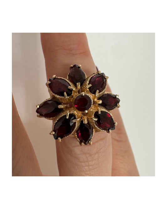 14K gold ring set with marquise-cut Garnets surrounding a round central stone.