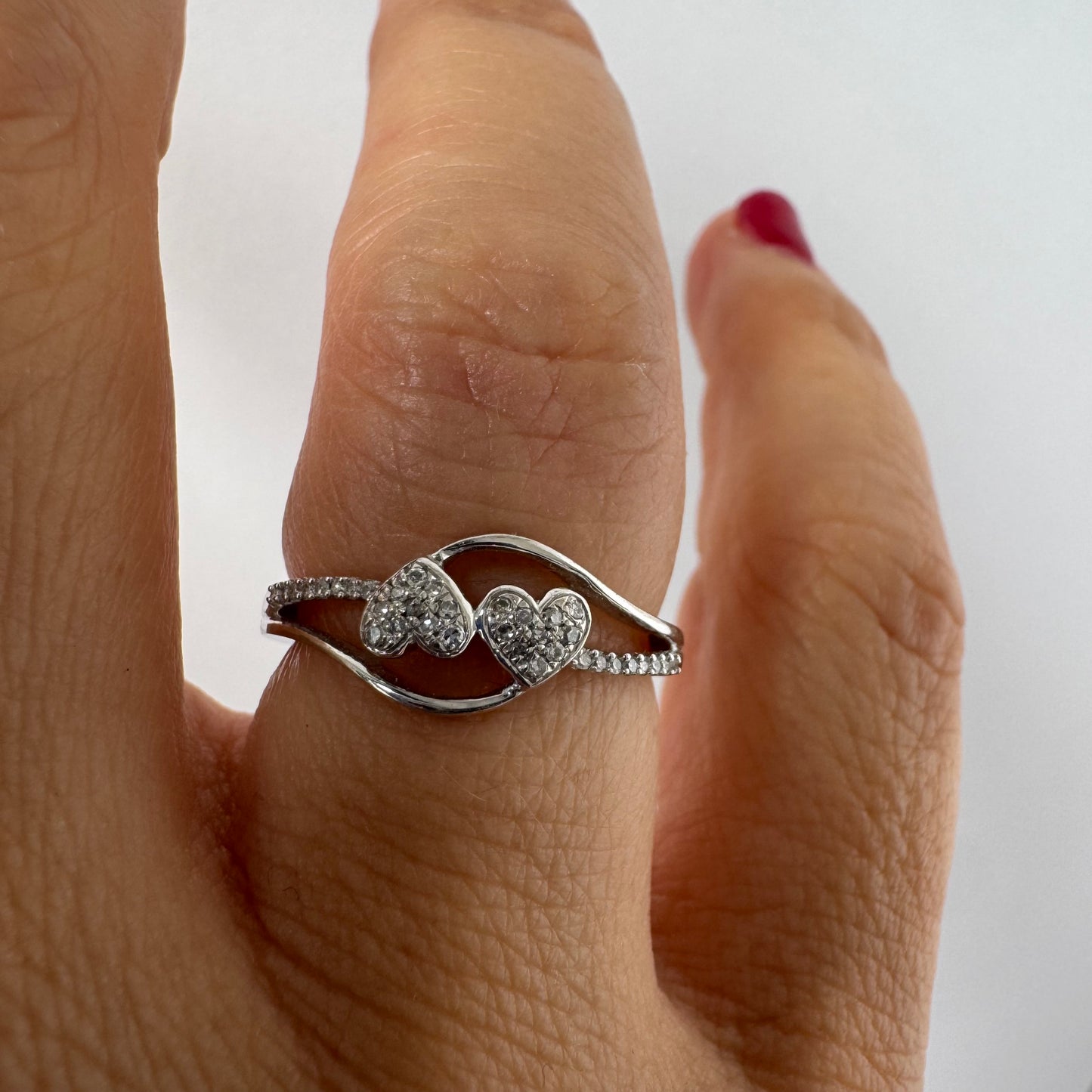 14K gold ring featuring a delicate and romantic design with two connected diamond hearts