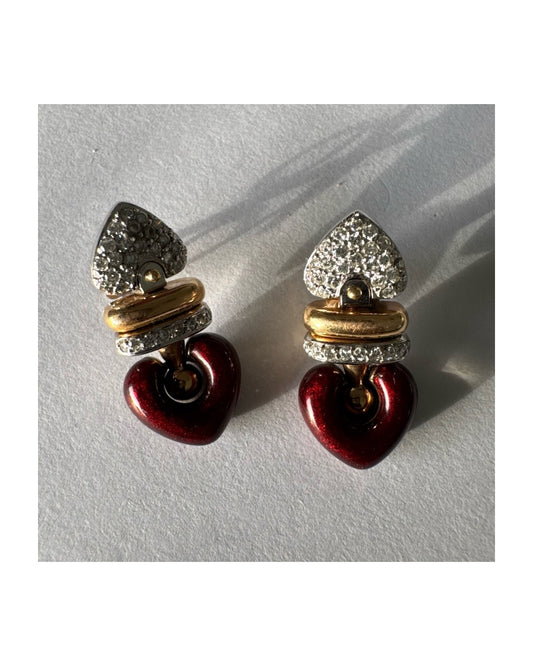 עגילי זהב 18 קראט בשילוב זהב צהוב ולבן, משובצים יהלומים בחלק העליון ובחישוק מרכזי, ובתחתית תליון לב אדום בגימור מבריק.