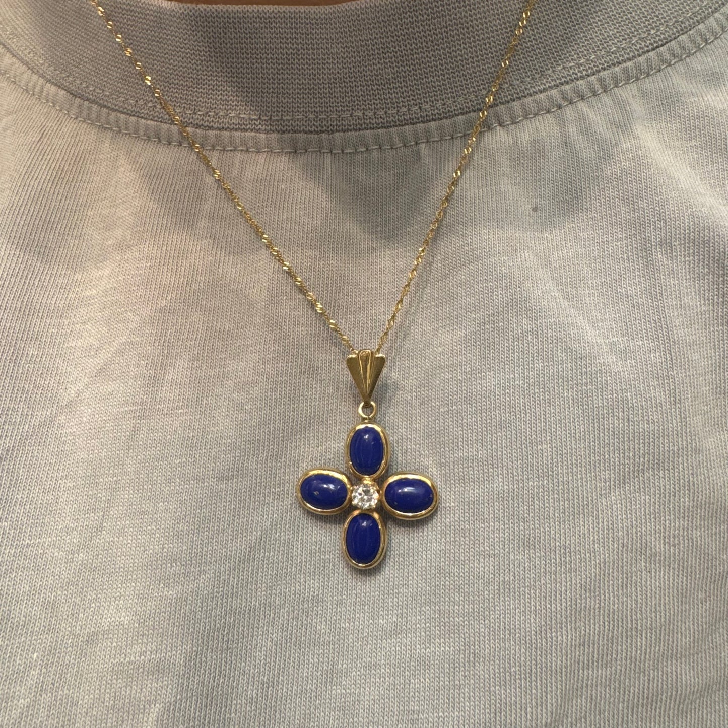 תליון זהב צהוב 14 קראט בעיצוב פרח סימטרי, משובץ ארבע אבני לפיס לזולי בגימור קבושון אובלי ובמרכזן יהלום עגול בוהק.