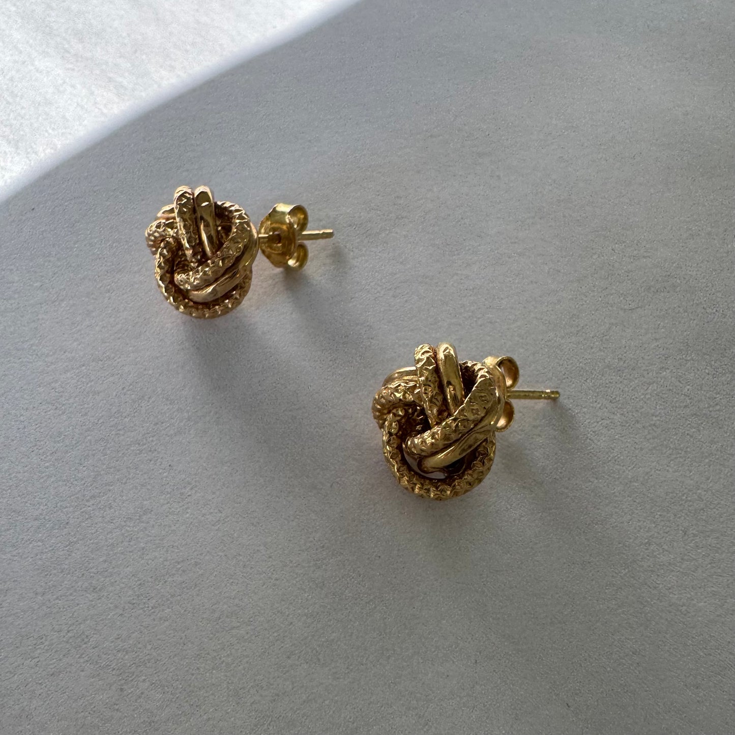 עגילי זהב צהוב 18 קראט בעיצוב קשר פיסולי, עם טקסטורה עשירה המדגישה את עומק וצורת הזהב.