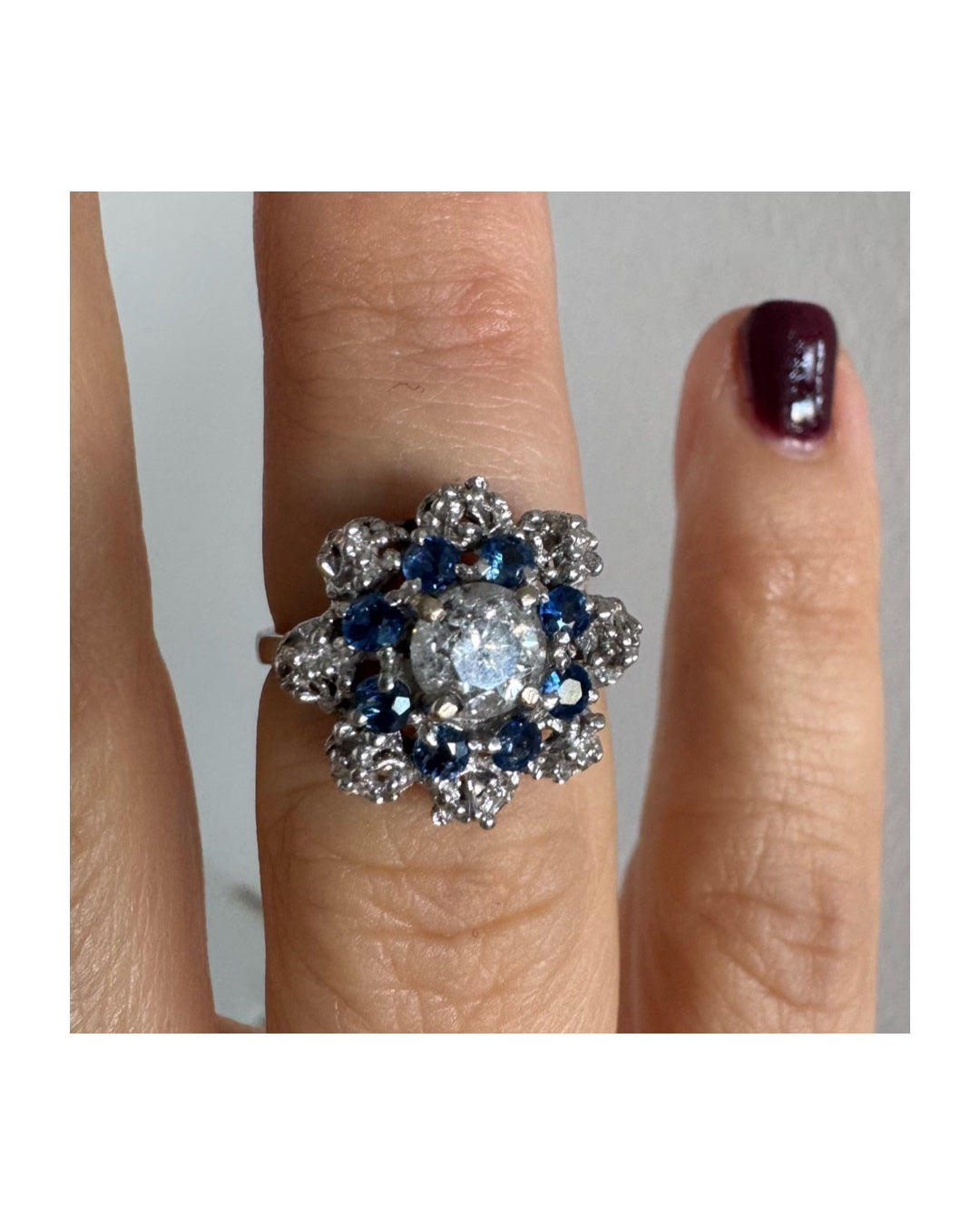 18K gold ring featuring a large round Diamond at the center, surrounded by a floral halo of purple -blue Tanzanite and & Diamonds.