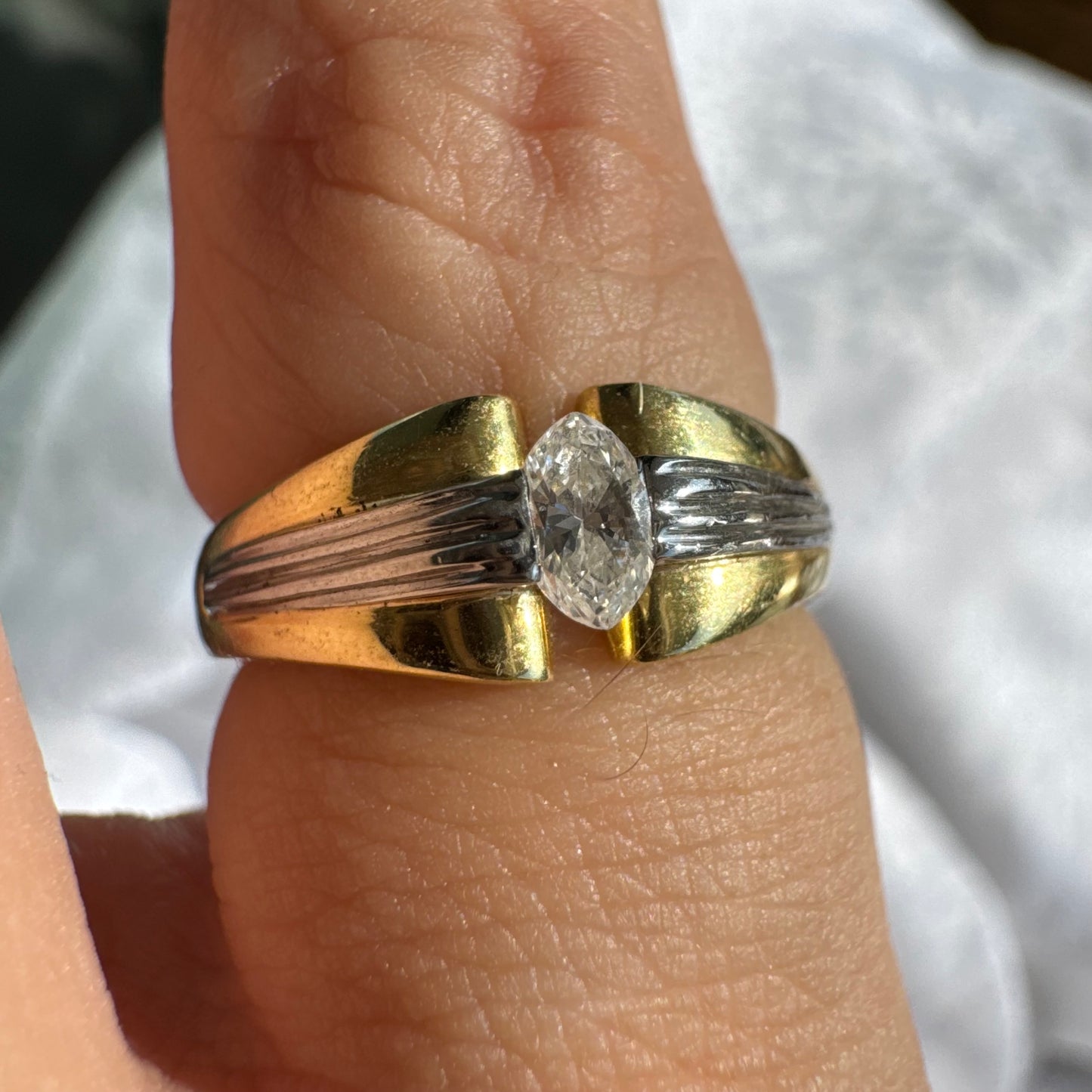 טבעת זהב 18 קראט בעיצוב דו-גוני של זהב צהוב ולבן, משובצת יהלום בחיתוך מרקיזה. 
