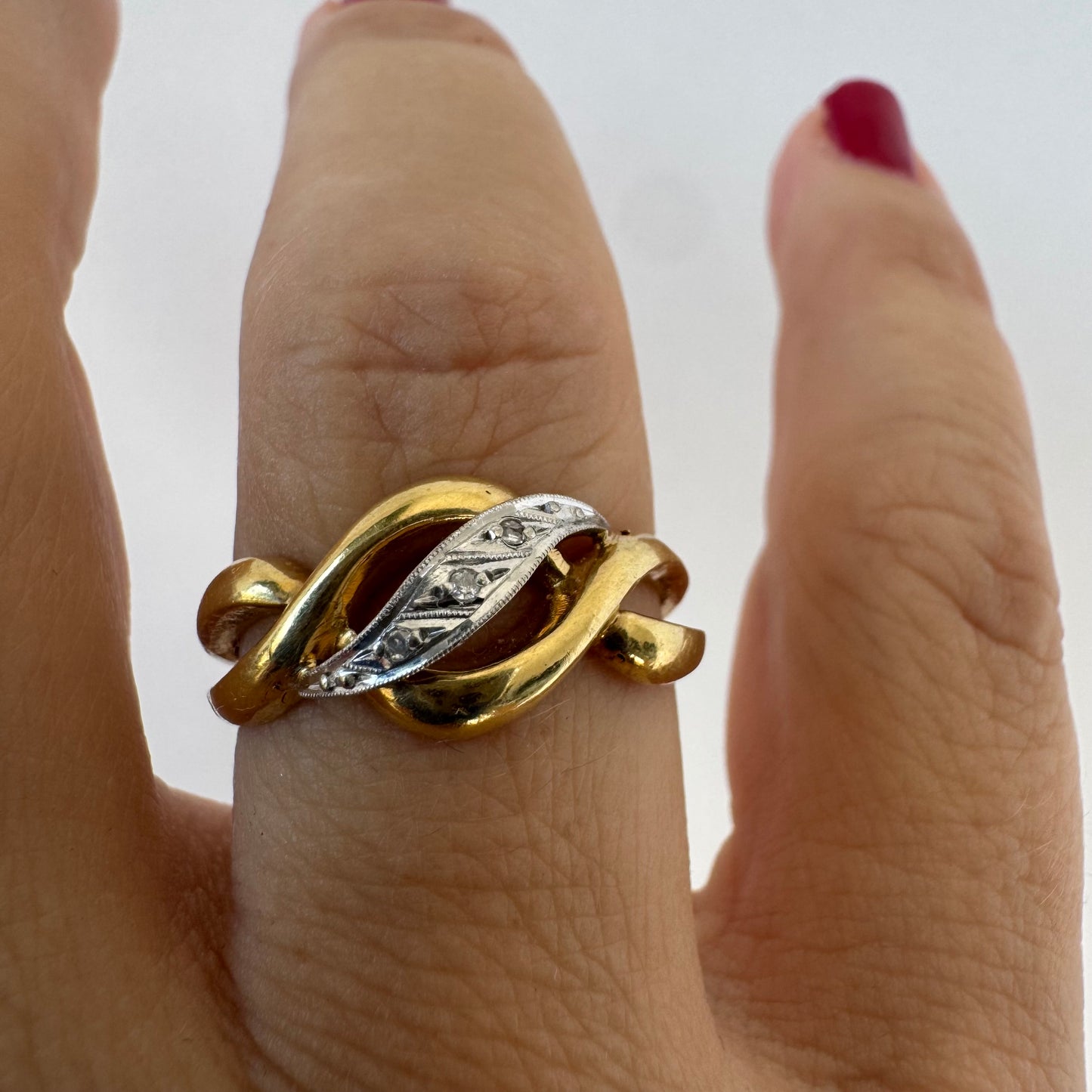18K gold knot-style ring featuring a white gold center accented with delicate Diamonds.