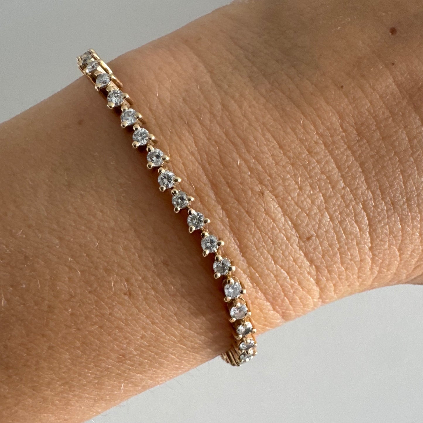 14K gold tennis bracelet set with a continuous line of round Diamonds, creating a delicate and elegant sparkle.