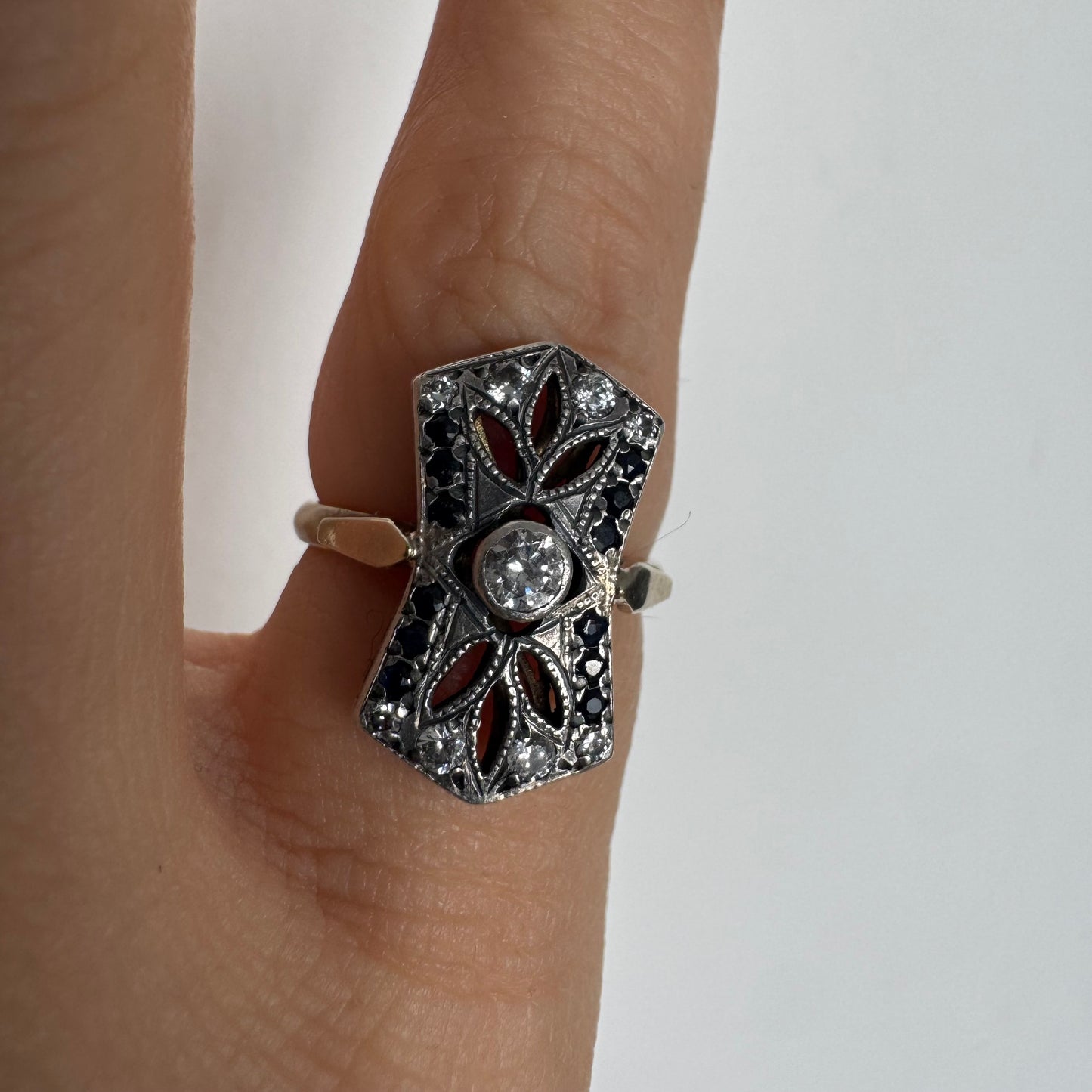 14K gold Art Deco ring set with a central Diamond, framed by deep blue Sapphires and accent Diamonds.