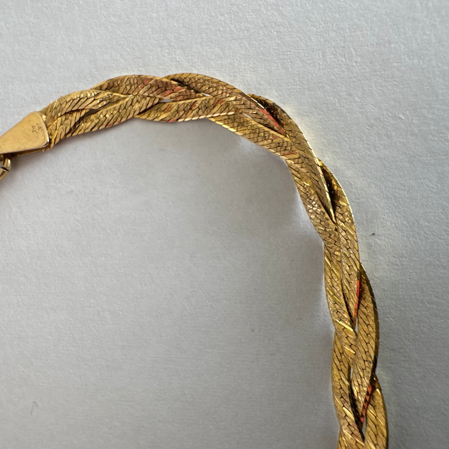 צמיד זהב צהוב 10 קראט בעיצוב קלוע עם טקסטורה עדינה שמחזירה אור וברק רך.