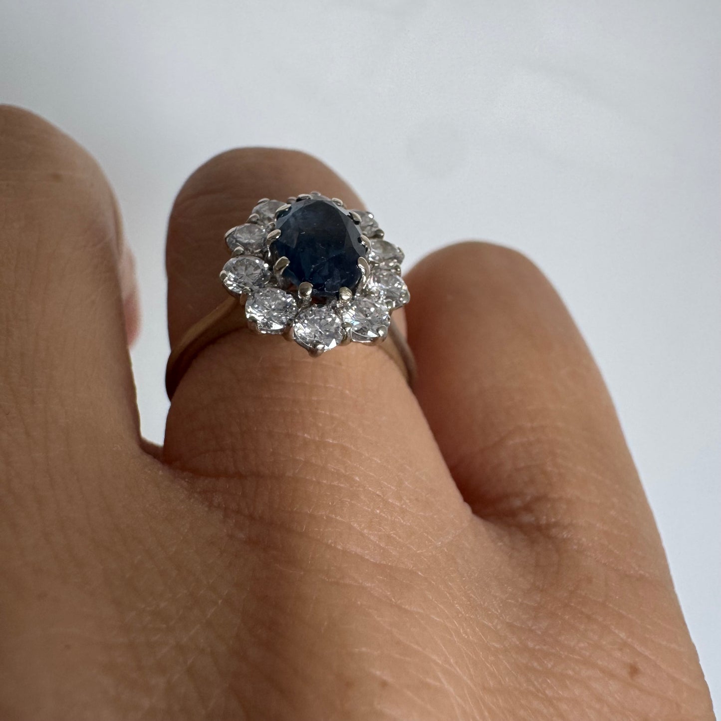 18K gold ring featuring a deep blue Sapphire at its center, surrounded by a sparkling halo of Diamonds
