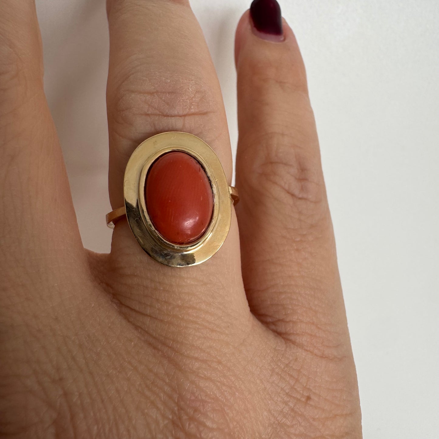 טבעת זהב 18 קראט משובצת אבן קורל אובלית בגימור קבושון, משובצת במסגרת חלקה ונקייה.