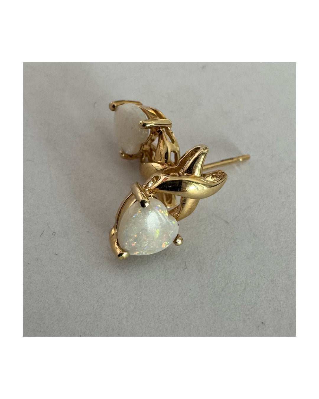 עגילי זהב צהוב 14 קראט משובצים אבני אופל בחיתוך לב, עם משחקי צבע טבעיים בגווני ירוק, ורוד וזהב.