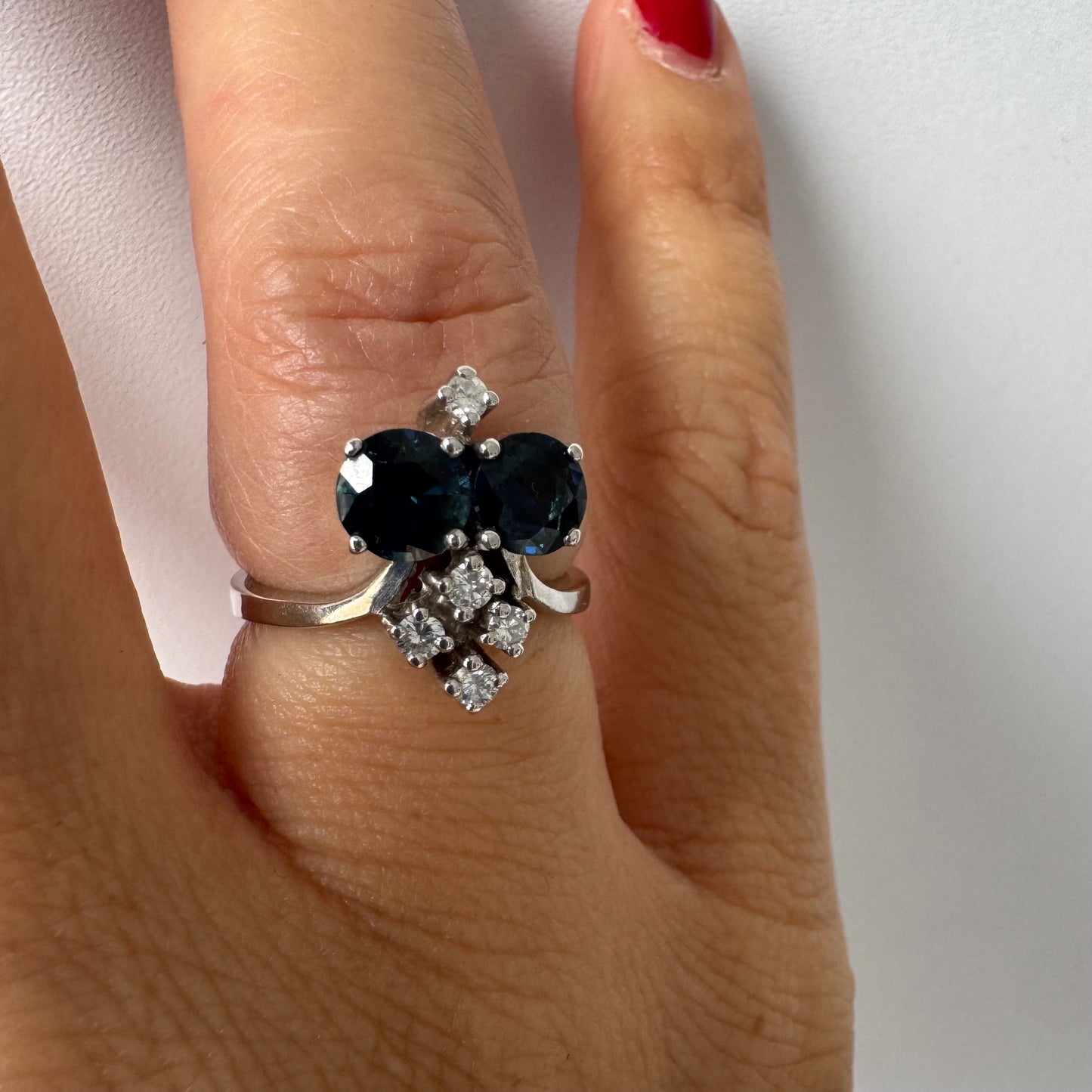 14K gold ring set with two deep blue oval Sapphires accented by clusters of brilliant white Diamonds.