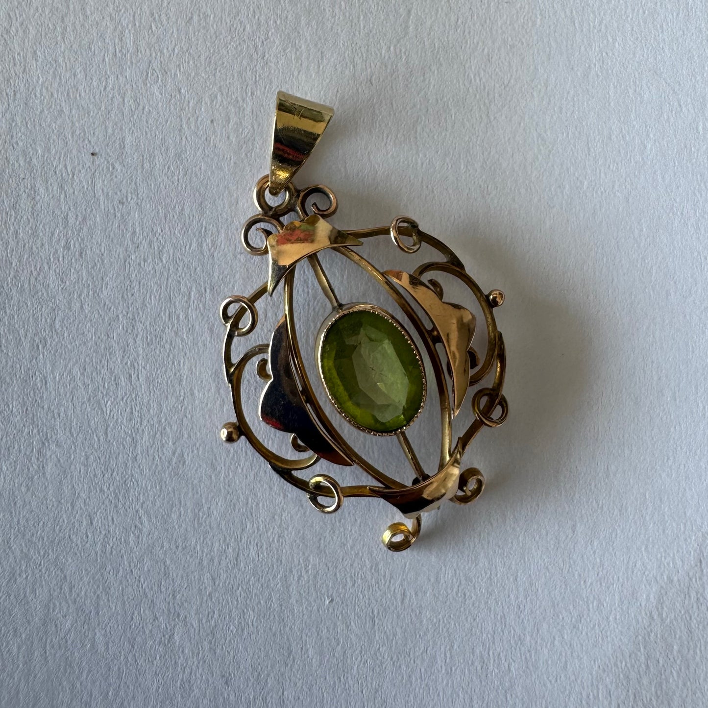 9K gold pendant featuring an oval-cut Peridot in a vibrant green hue.