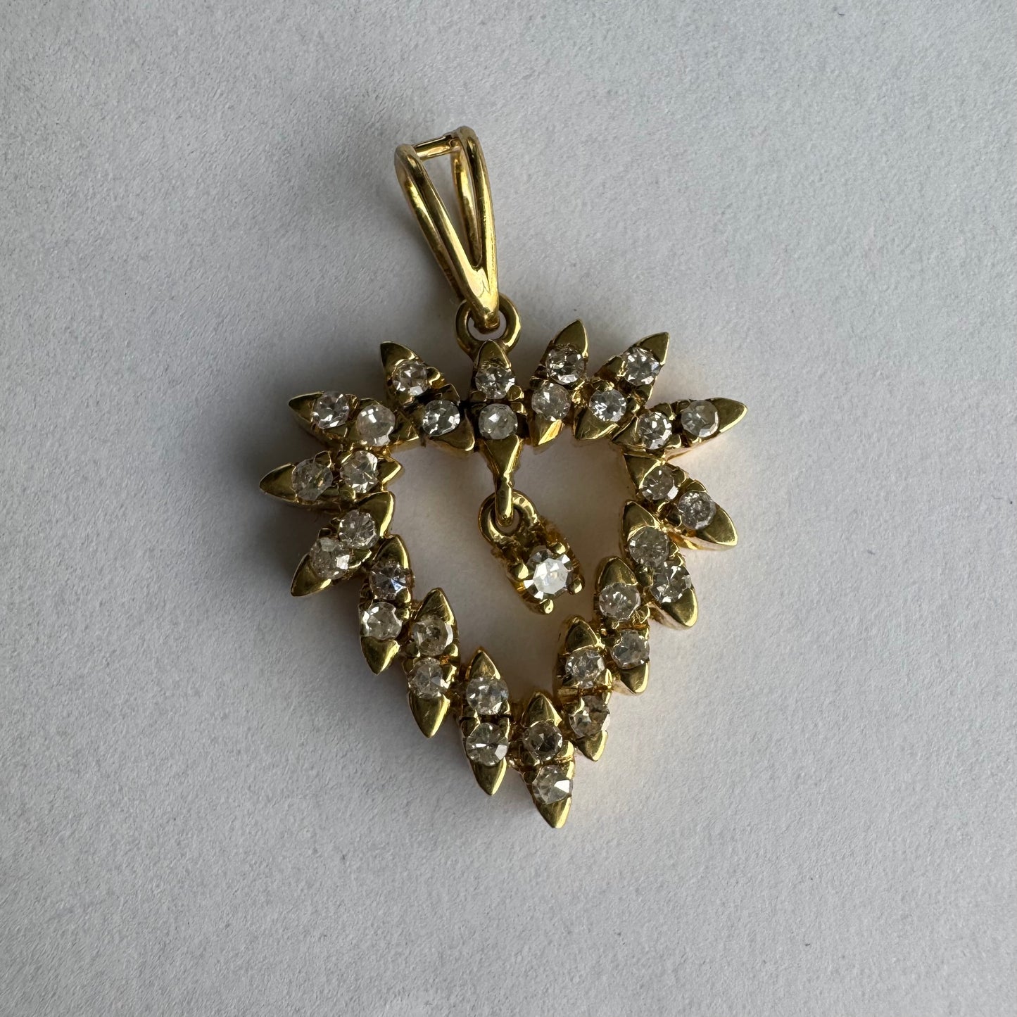 תליון זהב צהוב 14 קראט בצורת לב, משובץ יהלומים בסידור עדין היוצר מראה עשיר ומלא ברק.