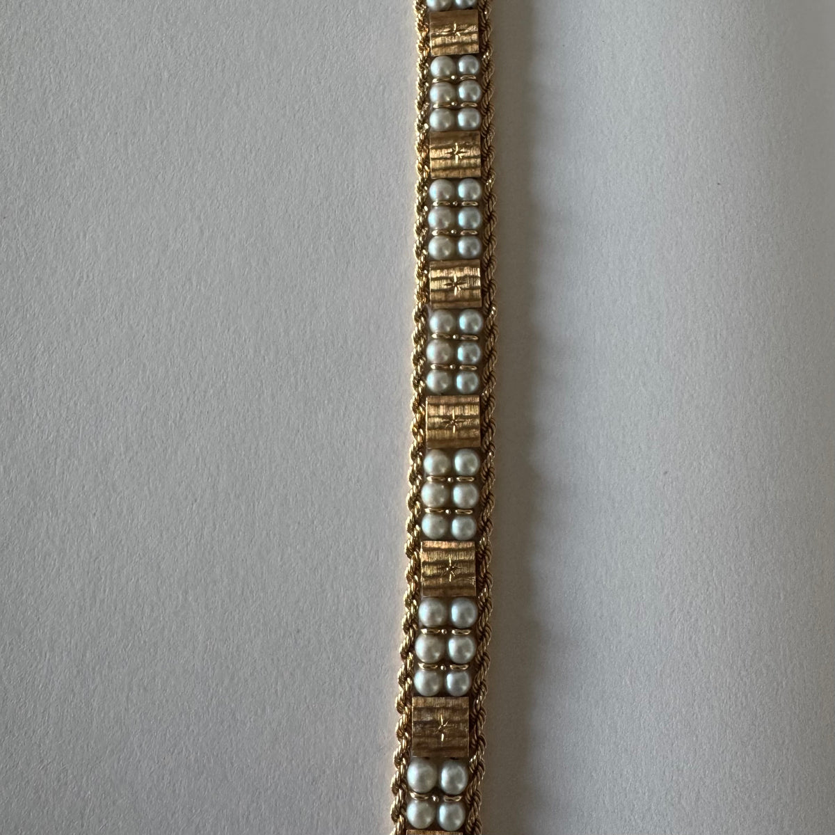 14K gold bracelet set with Pearls, featuring intricate rope-style detailing and textured geometric gold elements.