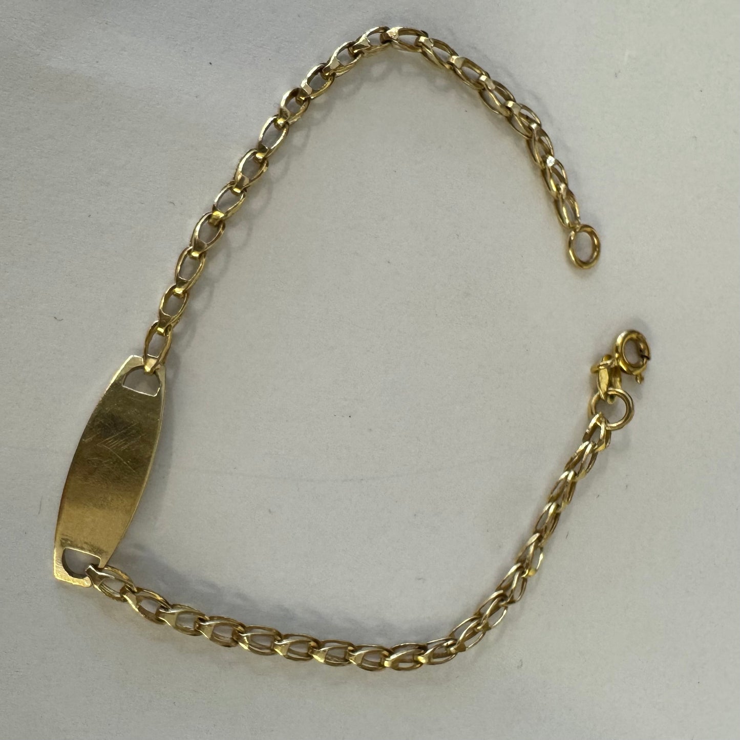 14K gold bracelet featuring a smooth ID plate and a delicate classic chain.