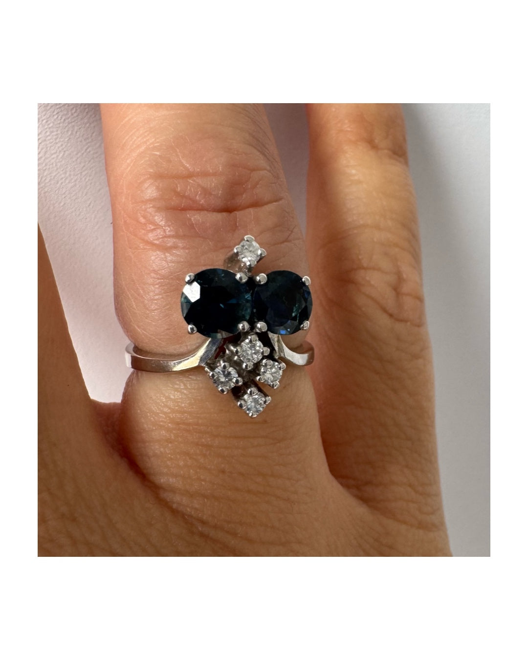 14K gold ring set with two deep blue oval Sapphires accented by clusters of brilliant white Diamonds.