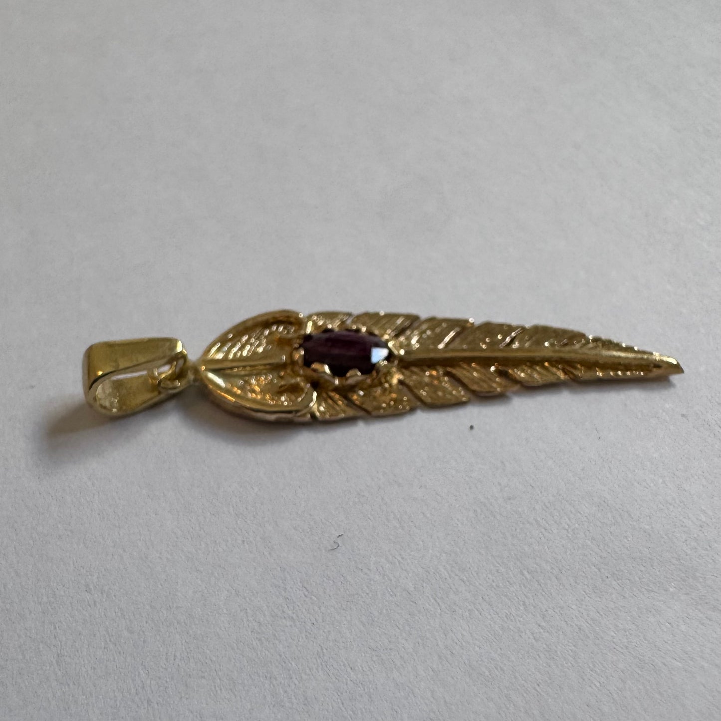 14K gold feather pendant set with a unique Ruby at its center.