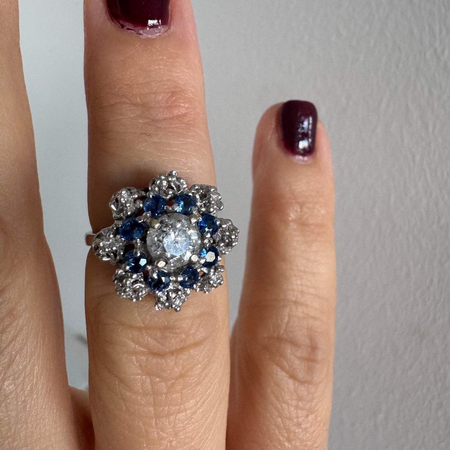 18K gold ring featuring a large round Diamond at the center, surrounded by a floral halo of purple -blue Tanzanite and & Diamonds.