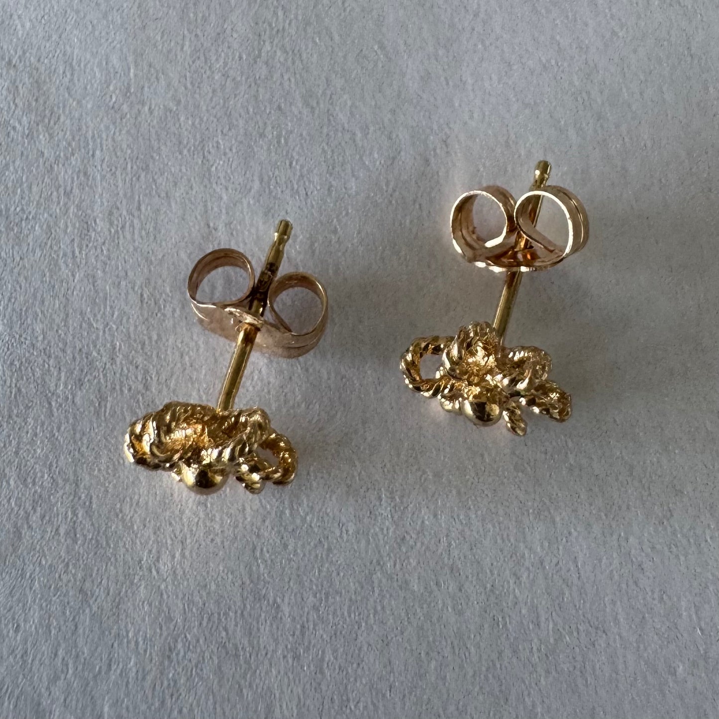 14K gold stud earrings designed as miniature flowers with fine textured details.