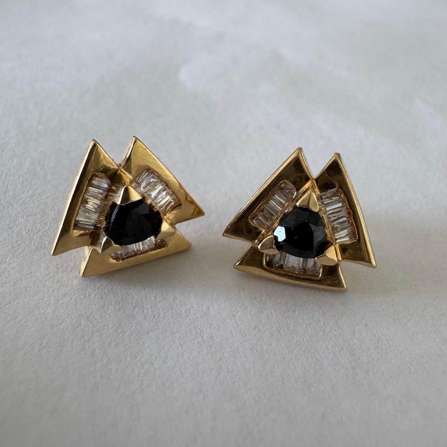 14K gold geometric stud earrings set with a Sapphire stone, surrounded by baguette Diamonds.