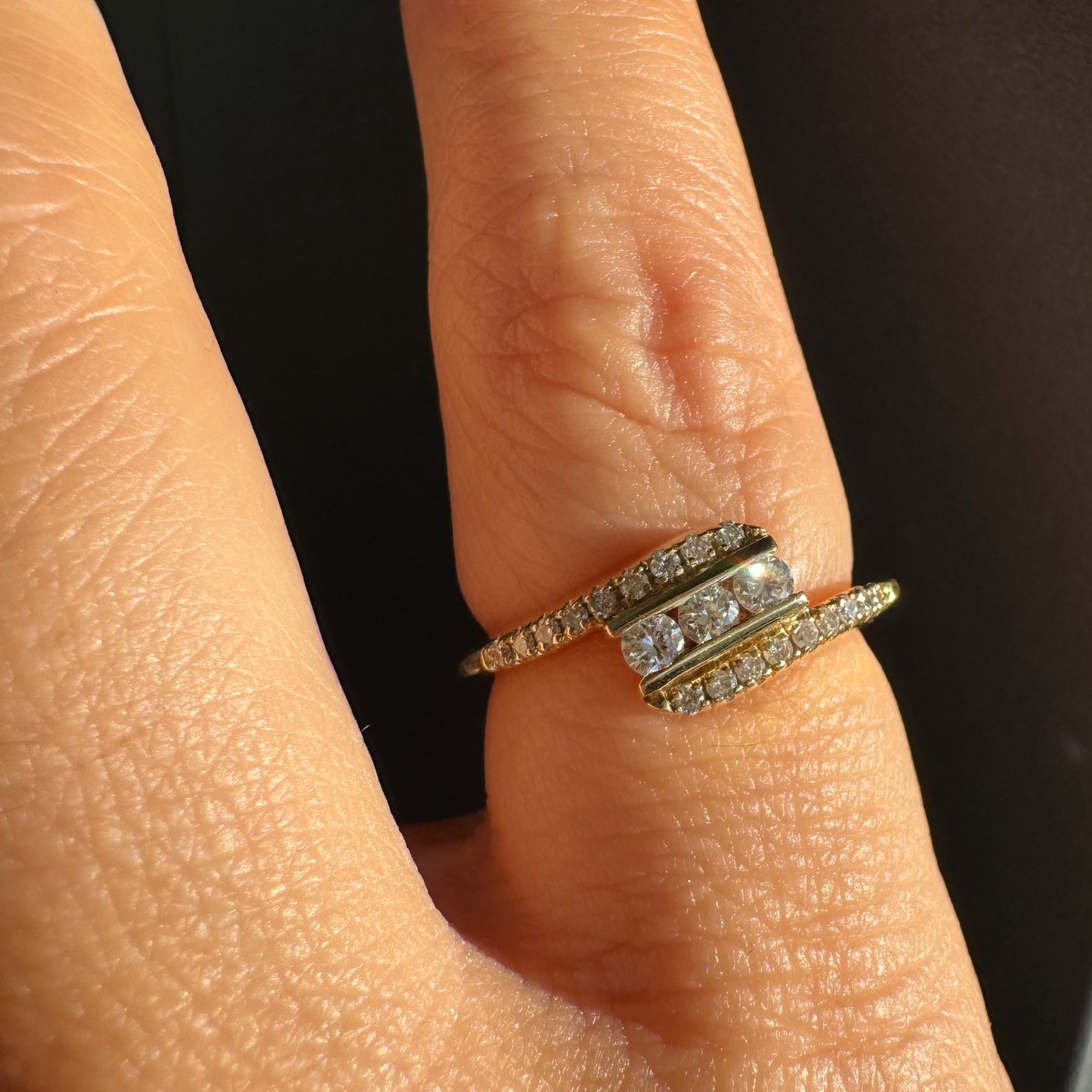 טבעת זהב צהוב 14 קראט בעיצוב ייחודי, משובצת שלושה יהלומים מרכזיים ושורות נוספות של יהלומים לאורך הזרועות. 