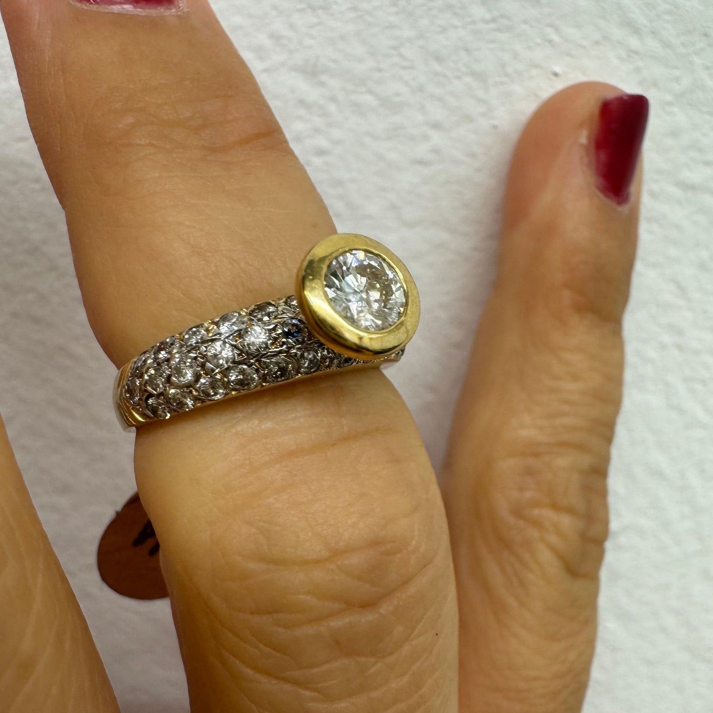 טבעת זהב צהוב 14 קראט משובצת יהלום עגול ויהלומים נוספים על הרצועה.