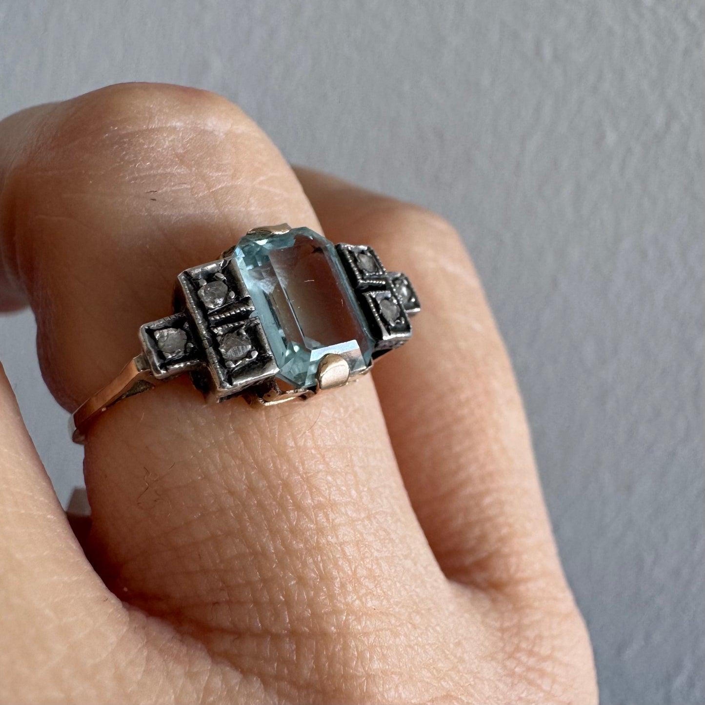 טבעת עתיקה מזהב 14 קראט, משובצת אבן אקוומרין מרכזית בחיתוך מלבני ויהלומים.