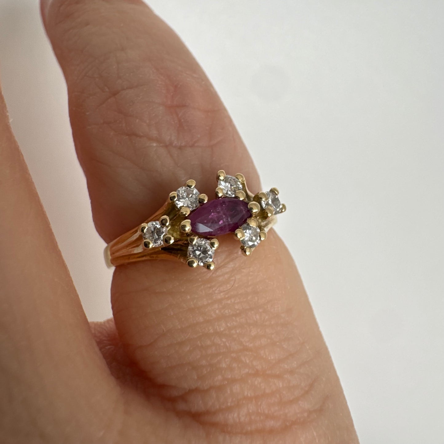 18K gold ring set with a marquise-cut Ruby accented by round Diamonds on each side.