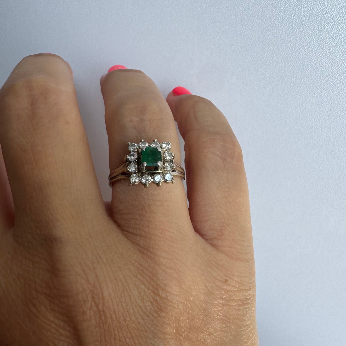 18K gold ring set with a vibrant square-cut Emerald surrounded by a sparkling halo of Diamonds.