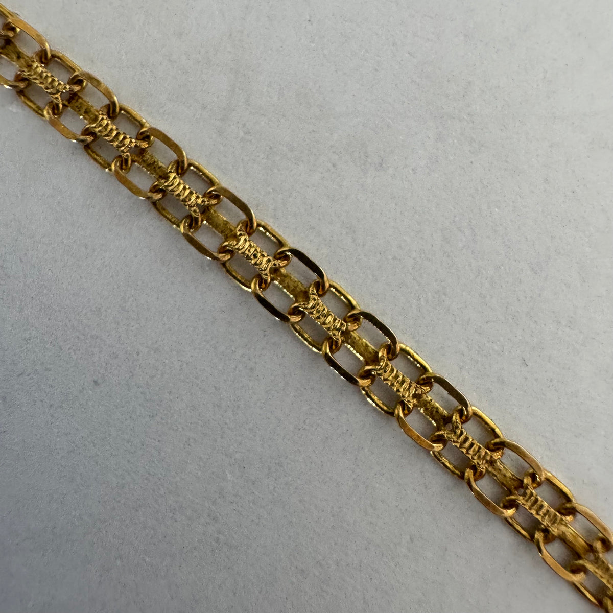 14K gold necklace featuring a flowing pendant design, set with a dark blue center Sapphire and a small Diamond above.