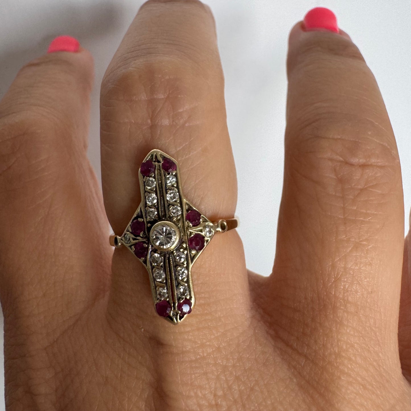 18K gold ring featuring a striking geometric design, set with a central Diamond surrounded by sparkling Diamonds and rich red Rubies.