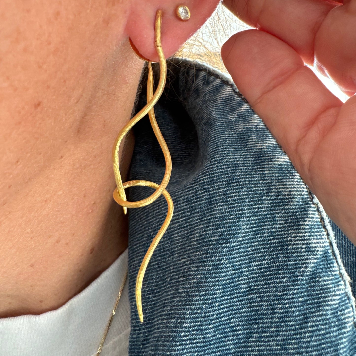 עגילי זהב צהוב 18 קראט מבית ה.שטרן, בעיצוב פיסולי וייחודי עם קווים זורמים ודינמיים.