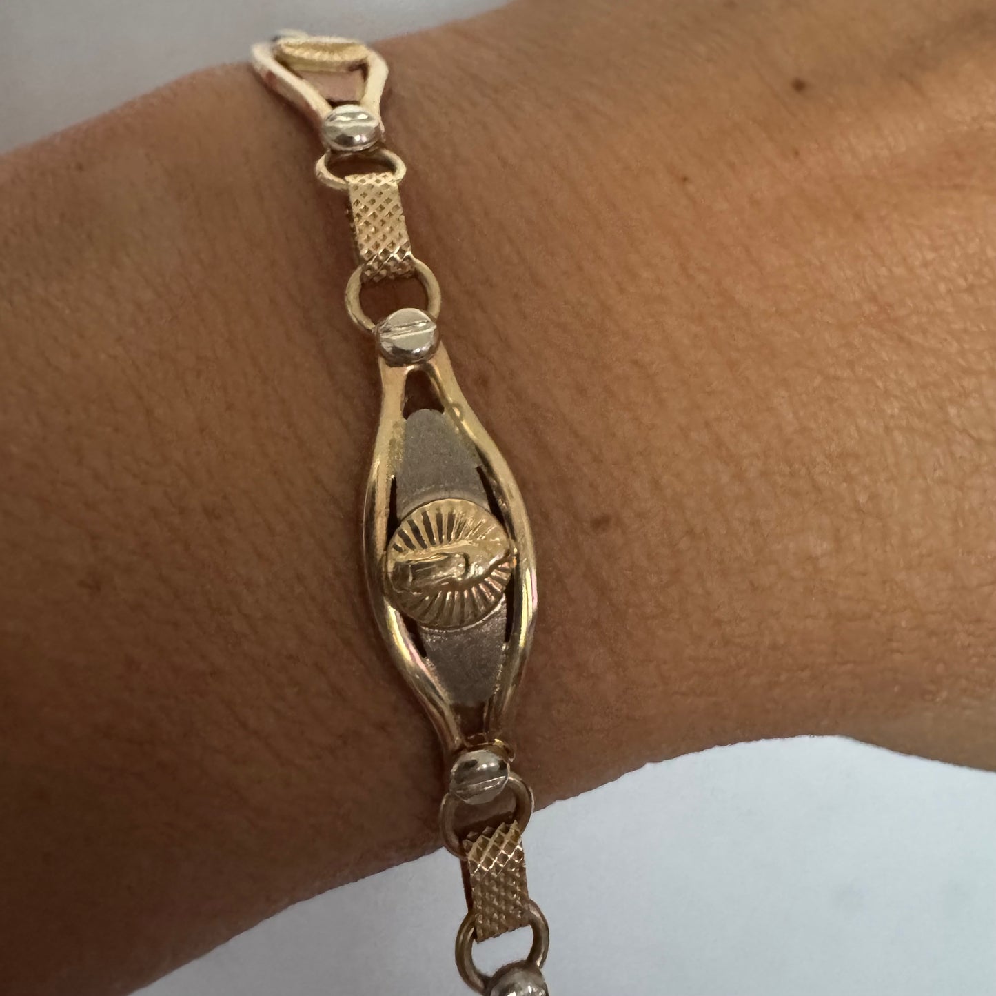 צמיד זהב צהוב 14 קראט עם אלמנט מרכזי בדמות מריה הקדושה, מוקפת קרני אור.