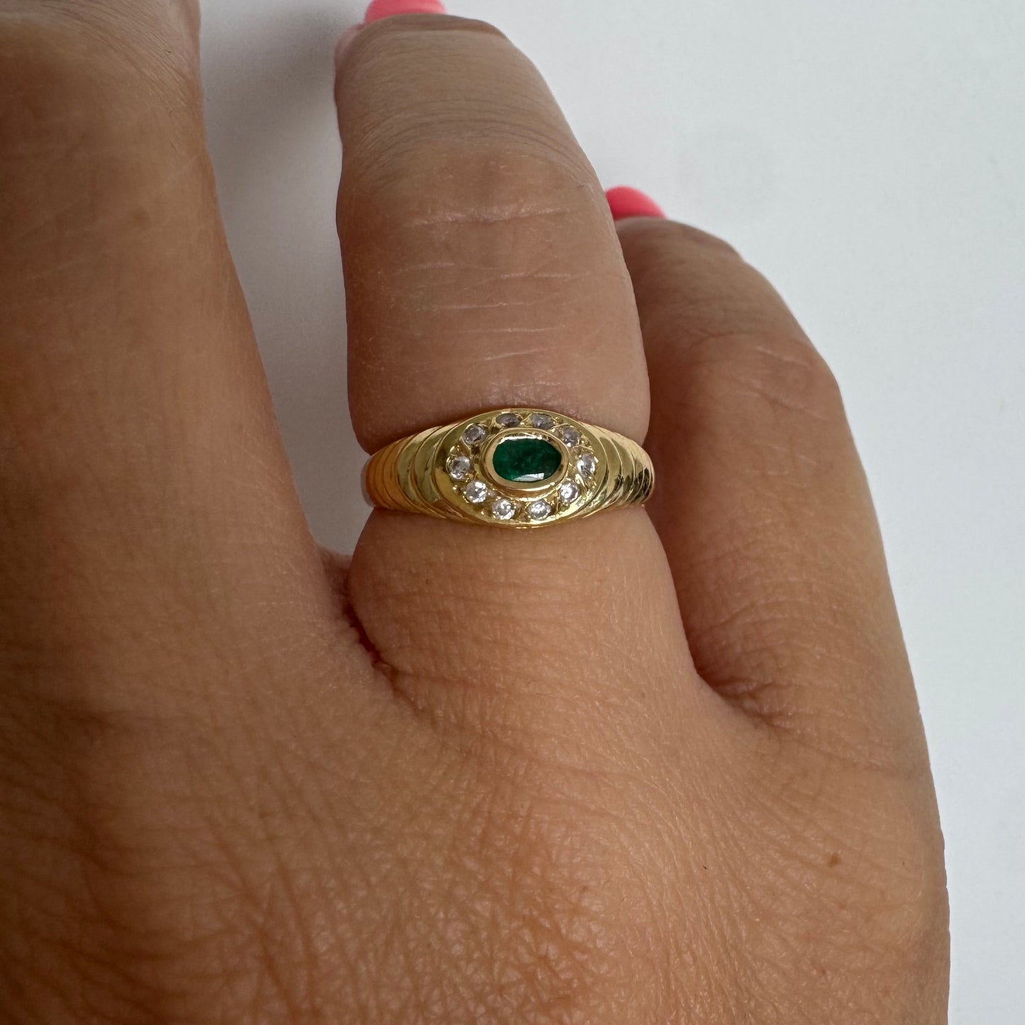 18K gold ring set with an oval Emerald at the center surrounded by Diamonds